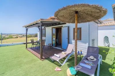 a patio with a umbrella and chairs and a table at El Paraíso Perdido in Conil de la Frontera