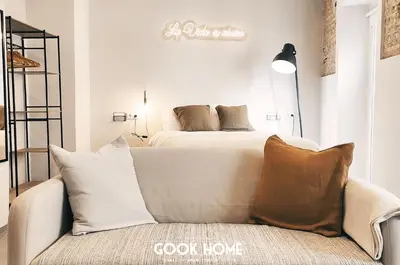 a bedroom with a bed and a couch with pillows at LalaSuites ARENAL in Jerez de la Frontera