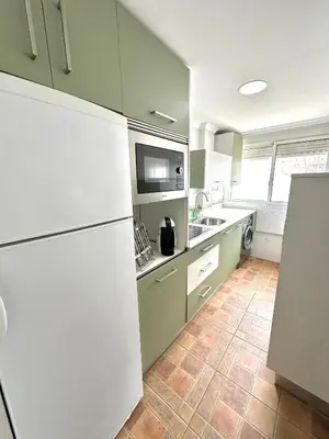 a kitchen with green cabinets and a white refrigerator at Encanto Jerezano Hideaway - Apartamento en Jerez - Apartment in Sherry in Jerez de la Frontera