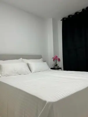 a large white bed with white sheets and a black curtain at Moderno y céntrico Apartamento de 2 dormitorios en El Puerto de Santa Maria in El Puerto de Santa María