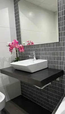 a bathroom with a sink and pink flowers on a counter at Moderno y céntrico Apartamento de 2 dormitorios en El Puerto de Santa Maria in El Puerto de Santa María