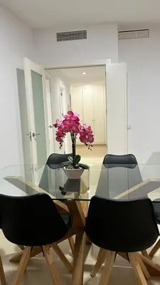 a glass table with chairs and a vase with flowers at Moderno y céntrico Apartamento de 2 dormitorios en El Puerto de Santa Maria in El Puerto de Santa María