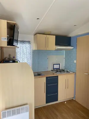 a kitchen with wooden cabinets and a stove top oven at Bungalow Mobilhome Agua en Chiclana de la Frontera, Cádiz in Chiclana de la Frontera