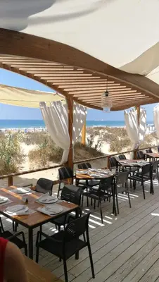 a group of tables and chairs on a deck at Bonito y confortable apartamento Novo Sancti Petri Barrosa Chiclana Cadiz in Chiclana de la Frontera