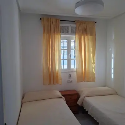 a bedroom with two beds and a window at Apartamento pinar del atlántico in Chiclana de la Frontera