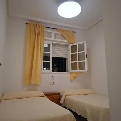 a bedroom with two beds and a window at Apartamento pinar del atlántico in Chiclana de la Frontera
