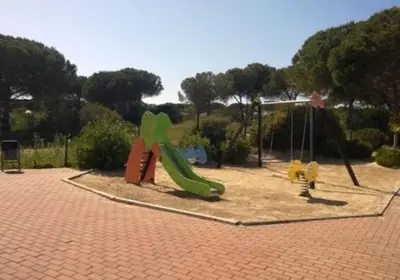 a playground with a green slide in a park at Adosado La Loma en Novo Sancti Petri in Chiclana de la Frontera