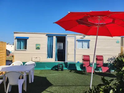 a patio with chairs and a red umbrella and a house at Franceses in Chiclana de la Frontera