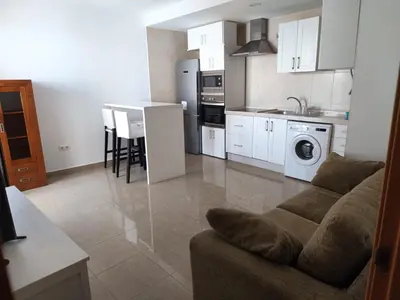a kitchen and living room with a couch and a table at Disfruta Jerez in Jerez de la Frontera