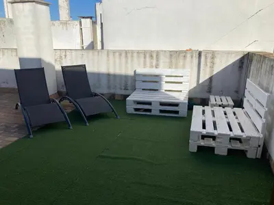 two chairs and a bench on a patio with green grass at Disfruta Jerez in Jerez de la Frontera