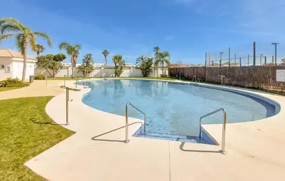a large swimming pool in a yard with palm trees at Gorgeous Apartment In Rota With Wifi in Rota