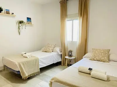 a room with two beds and a table and a window at Marisma Home in Chiclana de la Frontera