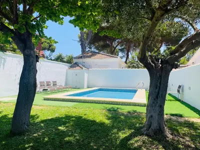 a swimming pool in a yard with two trees at Marisma Home in Chiclana de la Frontera