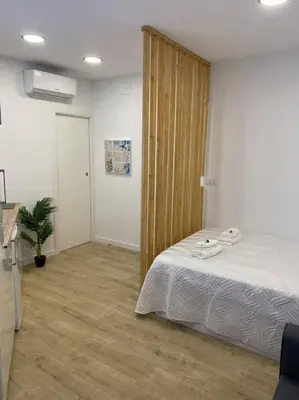 a bedroom with a bed and a wooden door at Coqueto Mini piso / Estudio/ 20 metros / playa / Wifi in Chiclana de la Frontera