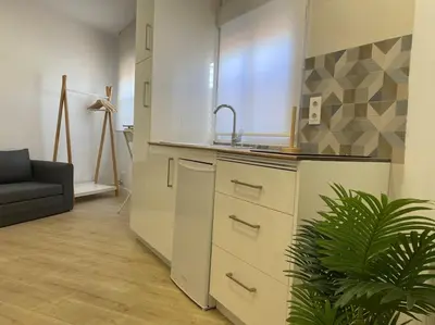 a kitchen with a sink and a couch in a room at Coqueto Mini piso / Estudio/ 20 metros / playa / Wifi in Chiclana de la Frontera