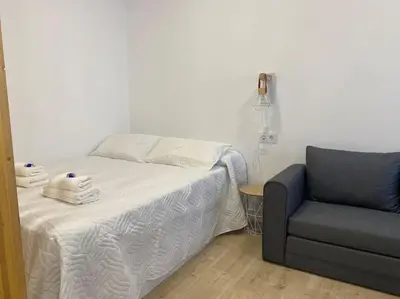 a bedroom with a bed and a blue chair at Coqueto Mini piso / Estudio/ 20 metros / playa / Wifi in Chiclana de la Frontera