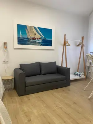a living room with a couch and a sail boat on the wall at Coqueto Mini piso / Estudio/ 20 metros / playa / Wifi in Chiclana de la Frontera