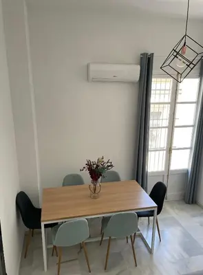 a dining room table with chairs and a vase with flowers at Dublin apartment in El Puerto in El Puerto de Santa María