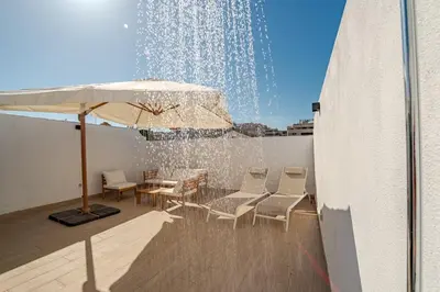 a fountain on the roof of a building with chairs and an umbrella at Dublin apartment in El Puerto in El Puerto de Santa María