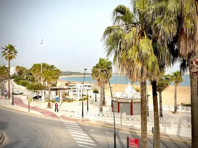 a street with palm trees next to a beach at MyChoice Casa Lilia in Rota