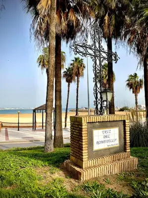 a sign in front of a beach with palm trees at MyChoice Casa Lilia in Rota