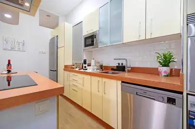a kitchen with white cabinets and a stainless steel refrigerator at Apartamento Casa Pili in El Puerto de Santa María