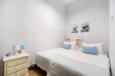 a white bedroom with a bed and a dresser at Apartamento Casa Pili in El Puerto de Santa María