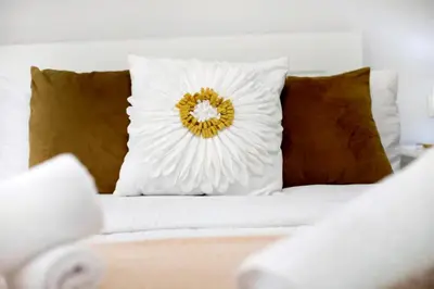 a white pillow with a flower on a bed at Apartamento Casa Pili in El Puerto de Santa María