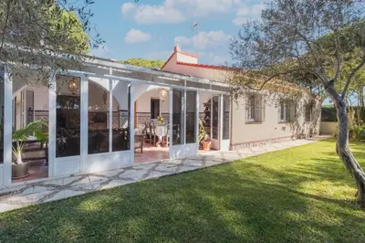 a house with a conservatory with a lawn at Cadizz - Villa Verde- La Barrosa - ideal familias y grupos de amigos in Chiclana de la Frontera