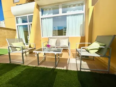 a patio with two chairs and a table and a window at GATU SIROCO junto la playa, piscina, aire acc, terraza, 