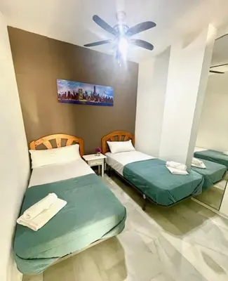 two beds in a room with a ceiling fan at GATU SIROCO junto la playa, piscina, aire acc, terraza, 