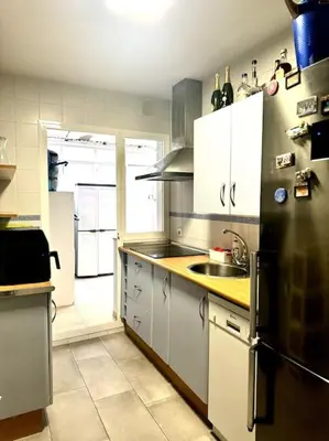 a kitchen with white cabinets and a black refrigerator at Jerez Rincón de Chloe y Julieta in Jerez de la Frontera