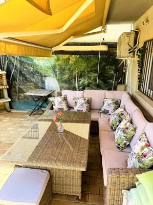 a patio with a couch and tables and an umbrella at Jerez Rincón de Chloe y Julieta in Jerez de la Frontera