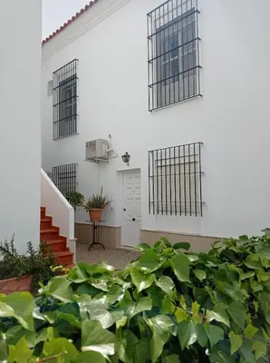 a white house with a bunch of green plants at Apartamento Crucero 2, la Jara in Sanlúcar de Barrameda