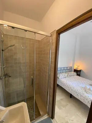 a bathroom with a shower and a sink and a bed at Apartamento Crucero 2, la Jara in Sanlúcar de Barrameda