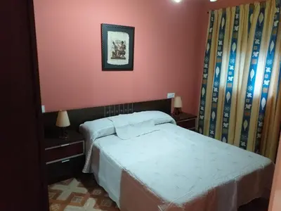 a bedroom with a bed and a pink wall at Casa araceli in Chipiona