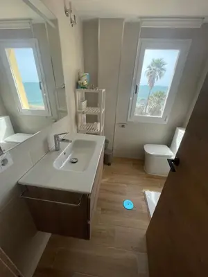 a bathroom with a sink and a toilet and a window at Primera Línea Playa el Manantial in El Puerto de Santa María
