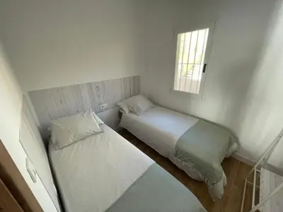 two beds in a small room with a window at Primera Línea Playa el Manantial in El Puerto de Santa María