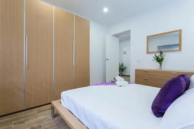 a bedroom with a large bed and wooden cabinets at Playa Santa Maria Moderno 3 Rooms in Cádiz