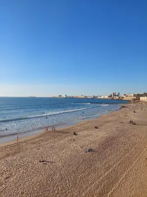 a beach with people on the sand and the ocean at Hogar del Sur by Gades Gestión in Cádiz