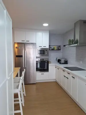 a kitchen with white cabinets and a stainless steel refrigerator at Casa Las Golondrinas in Rota