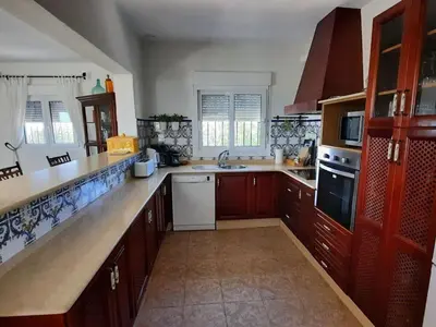 a large kitchen with wooden cabinets and a sink at »Casa Conil Buena Vista« in Conil de la Frontera