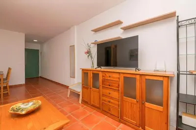 a living room with a wooden dresser with a tv on it at Oasis Playero in Chiclana de la Frontera