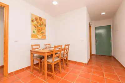 a dining room with a wooden table and chairs at Oasis Playero in Chiclana de la Frontera