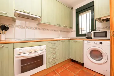 a kitchen with green cabinets and a washer and dryer at Oasis Playero in Chiclana de la Frontera