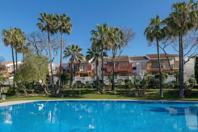 a large swimming pool in front of palm trees at Oasis Playero in Chiclana de la Frontera