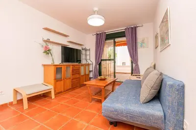 a living room with a blue couch and a tv at Oasis Playero in Chiclana de la Frontera