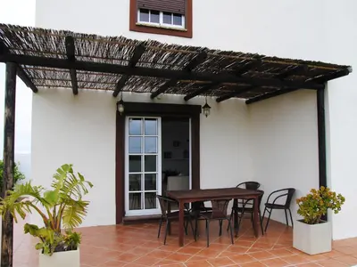 a patio with a wooden table and chairs at Torre Andaluz Villa con piscina 2 habitaciones in Cádiz