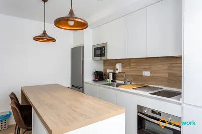 a kitchen with white cabinets and a wooden counter top at Buenos Aires by LiveWork in Cádiz
