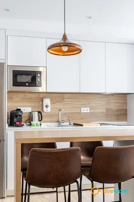 a kitchen with a sink and two bar chairs at Buenos Aires by LiveWork in Cádiz
